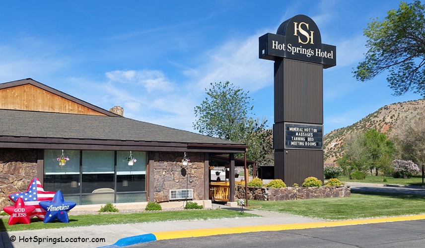 Hot Springs Hotel and Spa in Thermopolis Wyoming Hot Springs: The entrance of the hotel featuring a large wooden canopy with intricate decorations hanging from it. The entrance is flanked by stone pillars