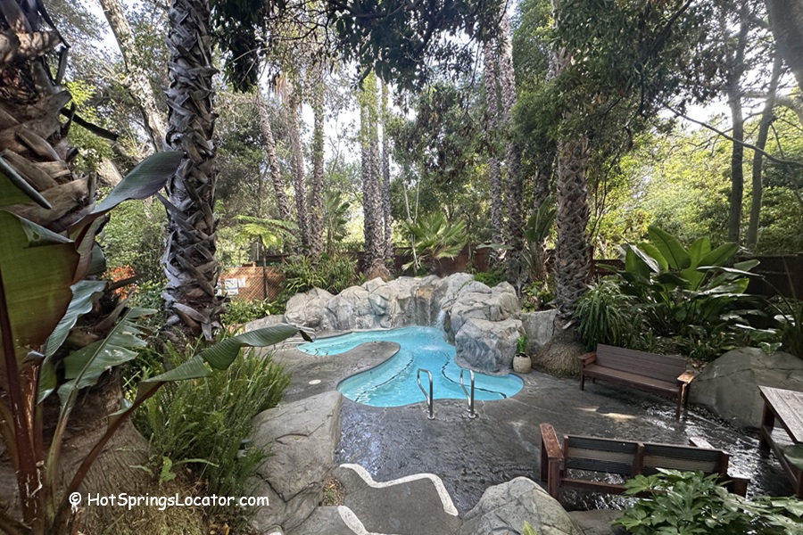 Sycamore Mineral Springs Resort & Spa California: The picture "Sycamore Mineral Springs Resort & Spa California outdoor hot tub area" displays a naturalistic hot tub set among rocks and palm trees, with benches and tropical plants creating a secluded, relaxing atmosphere.