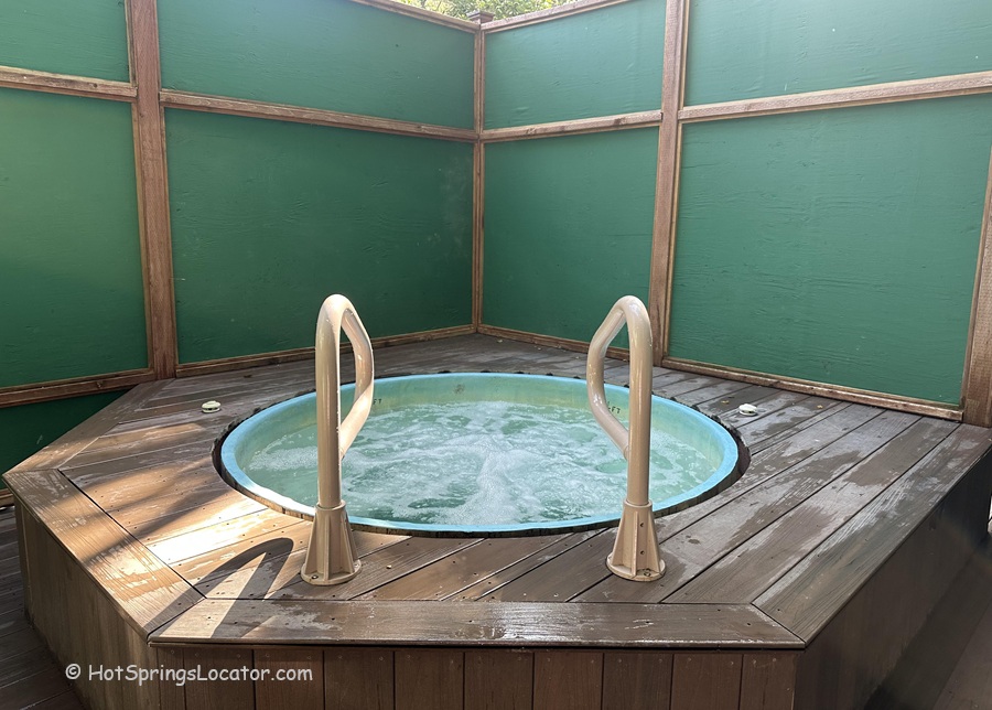 Sycamore Mineral Springs Resort & Spa California: The picture "Sycamore Mineral Springs Resort & Spa California private hot tub" features a round, bubbling hot tub set in a wooden deck and enclosed by green privacy panels, with handrails for easy access.