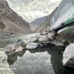 Cronks Canyon Hot Springs in Idaho: The picture "Cronks Canyon Hot Springs in Idaho canyon highway and river" displays a paved highway running alongside a fast-moving river, with rugged canyon walls and distant mountains beneath a cloudy sky.