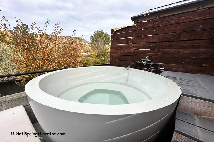 Kah-Nee-Ta Resort and Spa in Idaho: The picture "Kah-Nee-Ta Resort and Spa in Oregon private soaking tub on deck" shows a modern round soaking tub filled with water on a wooden deck, with a privacy fence and trees in the background.