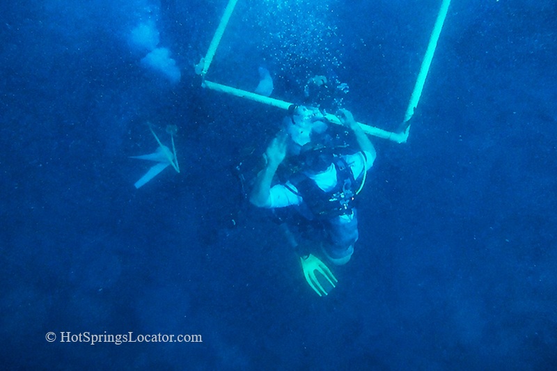 Homestead Crater Hot Springs in Utah: The picture "Homestead Crater Diver Underwater" captures a scuba diver in the deep, blue, mineral-rich water of the crater, holding a safety frame and releasing air bubbles.