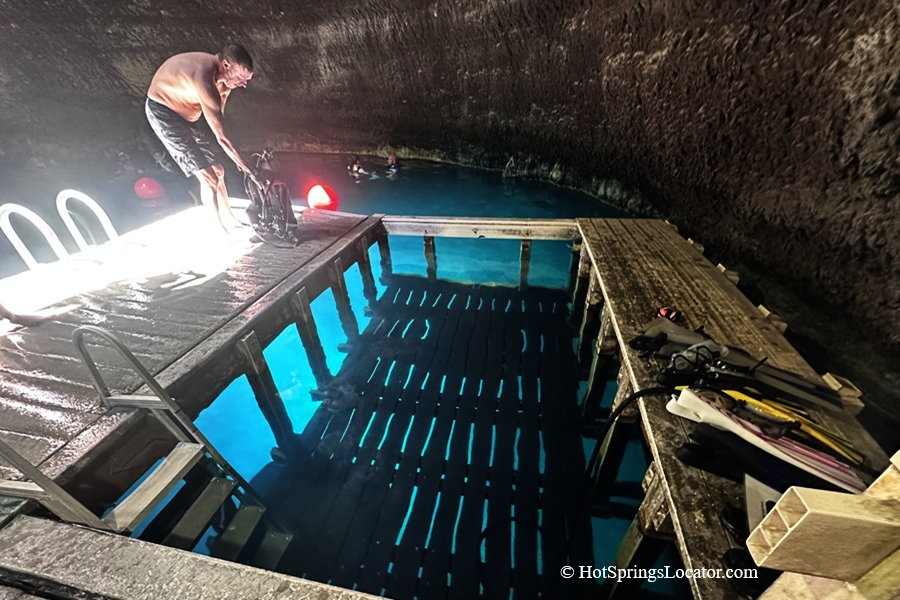 Homestead Crater Hot Springs in Utah: The picture "Homestead Crater Platform" shows a man preparing scuba gear on a wet wooden platform above the warm, clear water inside the crater, with more swimmers and equipment in the background.